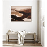 Abstract landscape canvas with layered brown and beige tones hangs above a rustic wooden bench draped with a cream throw and an open book on it.