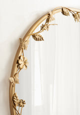 Round wall mirror with a gold metal frame adorned with detailed sculpted flowers, leaves, and butterflies arranged along the top and left edges.