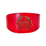 Wide red-orange snake-patterned collar featuring a centered gold-tone rhinestone crab accessory with green eyes, shown on a white background.