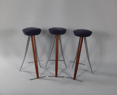 Three vintage style modernist bar stools with round seats arranged side by side