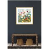 Square floral artwork with red, yellow, white, and pink wildflowers against a soft blue and green background, framed in a simple light-colored frame on a dark gray wall.