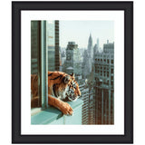 A tiger with orange and black stripes leans out of a tall building window overlooking Manhattan's skyline including the Chrysler Building during daytime.