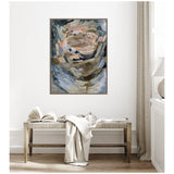 Abstract framed canvas with swirling beige, brown, gray, and muted pink brushstrokes, hanging above a wooden bench with a book and cream throw in a neutral-toned room.