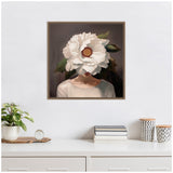 Portrait of a woman with a giant white flower obscuring her face, framed and hung on a white wall above a minimalist shelf with a plant and decorative jars.