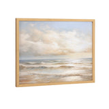 Framed print of a beach scene with gentle waves under a cloudy sky in soft beige, blue, and white tones, angled slightly from the side.