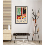 Colorful framed Henri Matisse print with fruit, a window with plants, and geometric patterns hanging on a white wall over a black bench in a minimalist room.