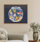 Framed illustration of a goldfish swimming inside a round glass fishbowl with pink and yellow aquatic plants against a dark blue background, hanging above a gray couch.