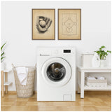 Two framed vintage-style baseball prints above a front-loading white washing machine, with a woven laundry basket on the left and a white table holding detergent and towels on the right.
