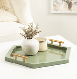 Hexagonal sage green tray with gold handles holding a white ceramic vase with dried flowers and a cream candle jar, set on a white table.
