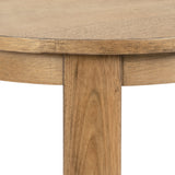Close-up of the natural wood grain and smooth edge of a round wood side table, highlighting the warm brown tones and seamless joint at the table's leg.