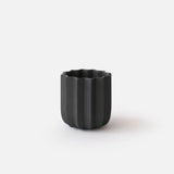 Matte black planter with a vertical ribbed texture and scalloped top edge, shown on a white background with soft shadows