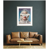 Framed wall art above a brown leather sofa depicts a woman with silver hair wearing a lace top and a large white moth covering her eyes, with moon phase symbols above her head.