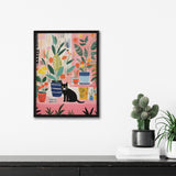 Colorful framed artwork of various whimsical potted houseplants with a black cat sitting in front, hanging on a white wall above a dark table with a cactus and books.
