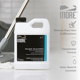 White plastic jug labeled MORE Acidic Cleaner with black and blue label, set next to a mop with a gray handle and white mop head on a tiled floor.
