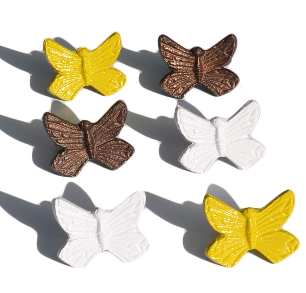 Set of six Vibhsa butterfly napkin rings in antique copper, yellow, and white finishes on a kitchen table.
