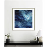 Square abstract artwork with swirling deep blue and gray tones and lighter blue highlights, framed in a light wood frame on a white wall above a black console table.
