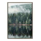 Framed canvas showing a misty evergreen forest reflected perfectly on a calm lake with soft fog above the treetops.