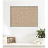 Rectangular beige pinboard framed in light wood featuring a white dashed lattice pattern, mounted on a white wall above a table with lamp, photo frame, and potted plant.