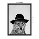 Black and white portrait of a wolf wearing a black fedora hat and a small pendant on its fur, set against a textured light gray background inside a black frame.