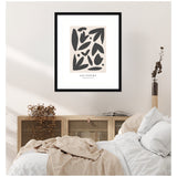 Framed abstract art print with dark organic shapes on beige background, titled 'Les Fleurs', hanging above a wooden cabinet and a bed with white and beige bedding.