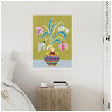 Colorful framed artwork of pink and white snowdrop flowers with blue leaves in a patterned vase against an olive green background, hanging above a wooden nightstand.