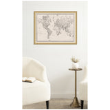 Vintage-style black and white world map printed on linen fabric framed in light wood, hanging on a white wall above two cream armchairs and a small brass side table with a white vase.