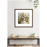 Framed wall art print depicting an olive branch with green olives and leaves against a soft, muted background, hanging above a wooden console table with decor.