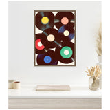 Framed canvas print featuring overlapping vinyl records with colorful center labels in yellow, pink, green, blue, and red on a white background, hung above a minimalistic shelf.
