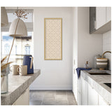 Tall narrow framed print with a beige background and dark green lattice pattern, hanging on a white kitchen wall between gray stone countertops.