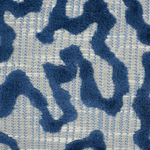 Close-up of Janis velvet pillow cover featuring irregular raised blue velvet shapes on a finely woven gray and cream background.