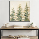 Abstract painting of three evergreen trees in muted greens and yellows with a gray frame, hung above a wooden table with books, a mug, and a white vase with a trailing plant.