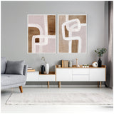 Two framed abstract canvas artworks featuring rhythmic white lines over beige and brown textured backgrounds, displayed side by side on a gray wall above a modern white and wood console.
