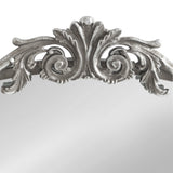 Close-up of ornate silver arch mirror frame top with symmetrical leaf and scroll detailing against a white background