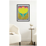 Framed abstract floral print with yellow, red, and green shapes against a white background with black dots, hanging above white chairs and a small brass table.
