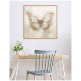 Framed canvas print of a softly detailed butterfly with neutral beige and brown tones hanging above a light wood desk and blue-gray chair, complemented by a small green plant.