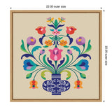 Symmetrical floral arrangement in a dark blue vase with white decorative patterns on a beige background, featuring vibrant pink, purple, orange, and green flowers and leaves.