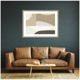 Abstract wall art with neutral beige, white, and brown curved shapes framed above a tan leather sofa with a small wooden coffee table and vase.