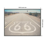 Desert highway stretching into distant mountains with Route 66 shield painted on the asphalt under a clear blue sky, sparse desert vegetation on sides.