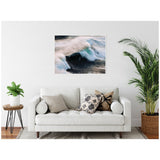 Framed canvas above a white sofa shows blue and white ocean waves crashing with mist on a dark sea, adding coastal energy to a minimalist living room with plants.