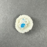 Small spherical white stilbite crystal cluster with a bright blue cavansite crystal embedded inside, displayed on a gray textured background.