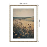 Framed print of a soft landscape painting showing wildflowers in the foreground with rolling hills and a muted sky in the background.