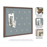 Rectangular blue pinboard with a subtle white botanical pattern and a dark wood frame, displaying two vintage black-and-white photos pinned with pushpins.