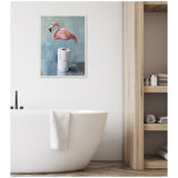 Pink flamingo standing on two rolls of white toilet paper against a muted teal background, framed and hanging above a white freestanding bathtub in a minimalist bathroom.