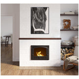Black and white close-up portrait of a horse's face framed above a lit fireplace on a white brick wall in a cozy living room.