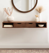 Wall-mounted dark wood floating side table with two drawers and open shelves, decorated with vases holding dried grasses under a round mirror.