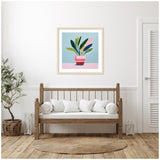Wooden bench with white cushions below framed colorful potted plant artwork on blue and pink background in a bright, white-walled room with natural decor.