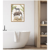 White bathroom with a freestanding tub beneath a framed canvas showing a zebra standing on an elephant inside a vintage clawfoot tub surrounded by palm leaves, and a small tiger cub on a circular mat.
