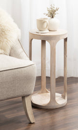 Light wood Dahl Wood Drink Table with five vertical curved cutouts and round top, styled with a white ceramic vase with dried flowers and a white mug on a saucer