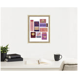 Framed wall art featuring colorful illustrated matchbook designs with Sagittarius symbols and text, displayed above a white desk with books, plant, and coffee cup.