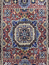 Hand-knotted Afghani wool rug with a central octagonal medallion in blue, brown, and cream, surrounded by geometric floral motifs and intricate borders.